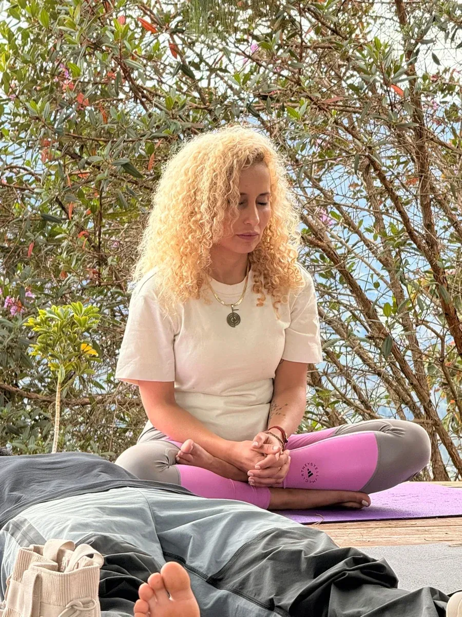 Leslye Rendón en un momento de quietud entre árboles, sentada con los ojos cerrados.